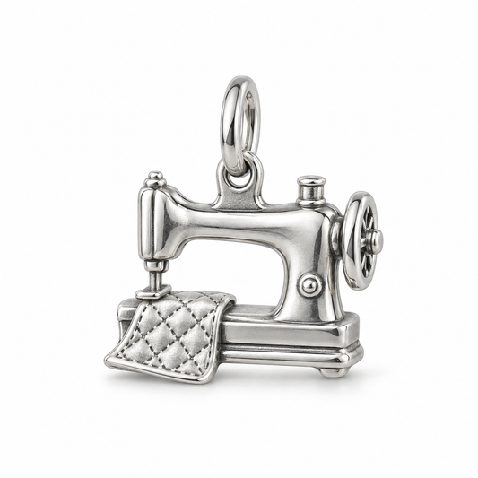 Sterling silver sewing machine charm featuring a detailed quilted fabric piece under the needle on white background.