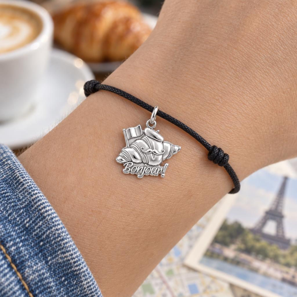Bonjour Croissant Charm Bracelet – Personalized Traveler Gift – worn on the wrist on a black cord bracelet