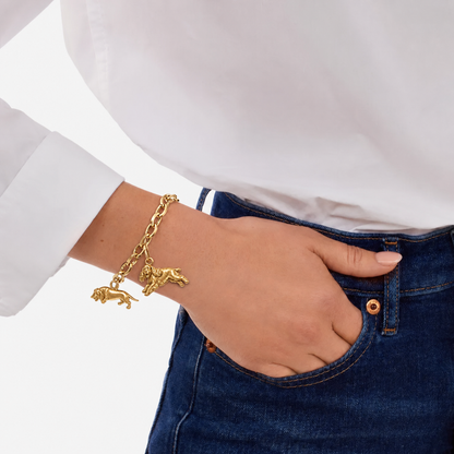 Model wearing a gold link bracelet with two dog breed charms paired with a white shirt.
